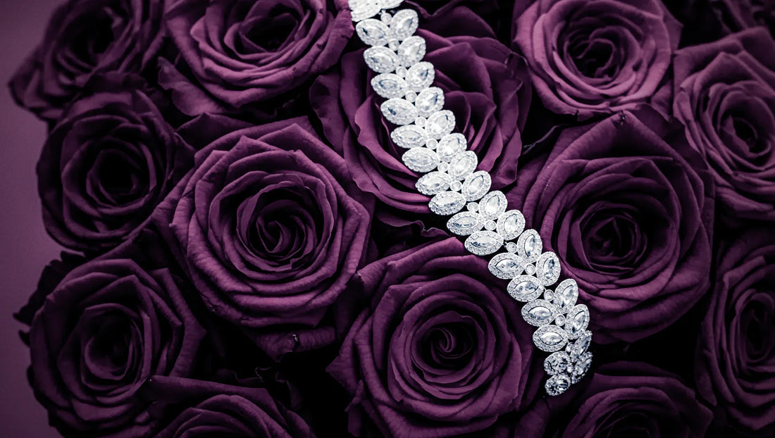 Silver diamond bracelet displayed on deep purple roses bouquet, luxury jewelry and floral arrangement