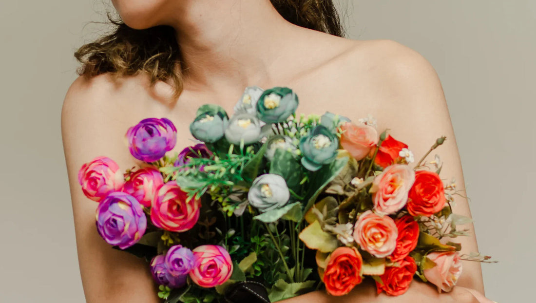 Close-up of woman holding vibrant bouquet of pink, purple, green, and orange roses against neutral background