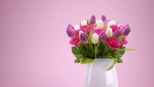 Vase with pink roses and purple and white tulips against a pink background