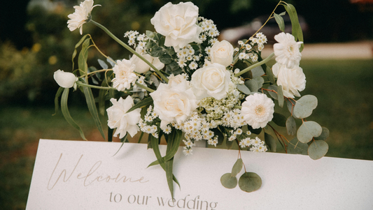 White floral wedding bouquet with roses and daisies on welcome sign