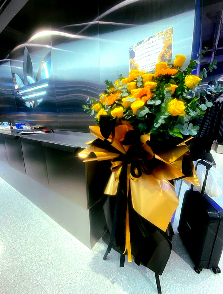 Bright yellow flower stand from BestBloomBuddy with colorful floral arrangements for grand opening celebration.