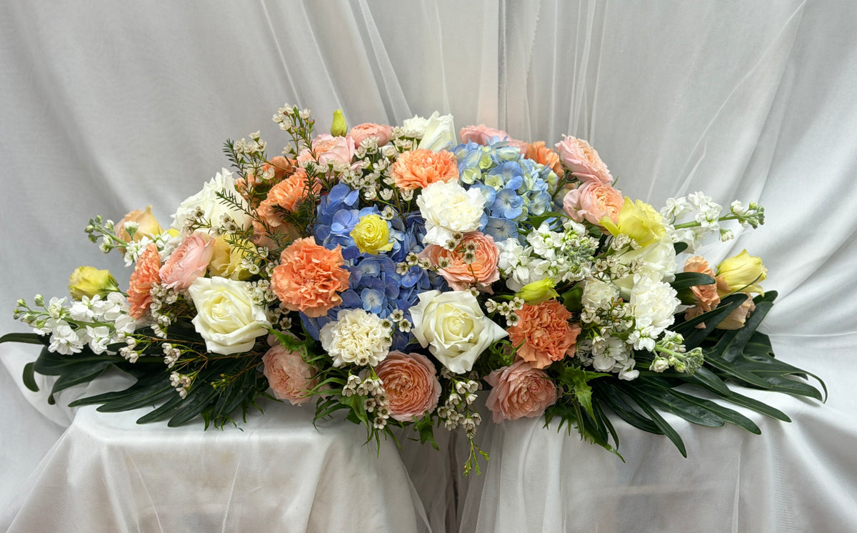 Beautiful flower centerpiece with peach and blue blooms, featuring a festive arrangement by BestBloomBuddy.